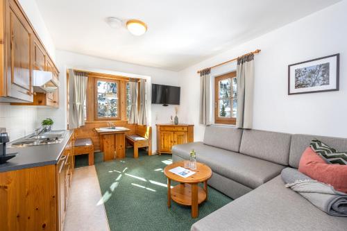 een woonkamer met een grijze bank en een keuken bij Apparthotel Zirbenhof in Obertauern