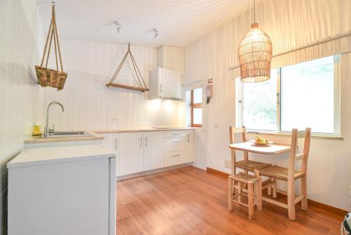 a kitchen with white cabinets and a table and chairs at Salema Eco Camp - Sustainable Camping & Glamping in Salema