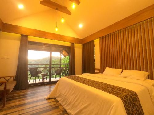 a bedroom with a large bed and a balcony at The Wild Trails Clarks Exotica , Munnar in Munnar