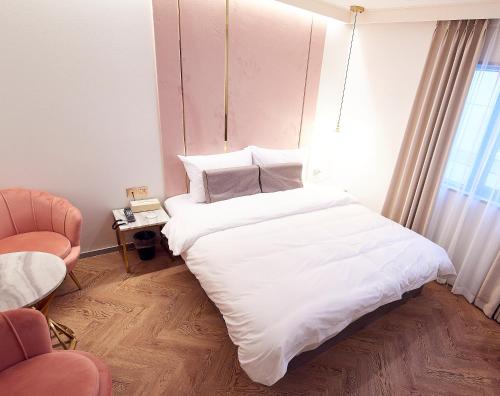 a bedroom with a large white bed and a chair at 사직 덴바스타 시그니처 호텔 in Busan