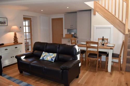 a living room with a leather couch and a table at Heron Cottage, Port o Tay in Pitlochry