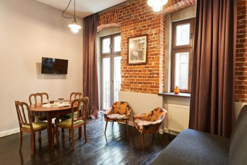 a dining room with a table and chairs and a brick wall at Apartament Patisserie by Good Time in Łódź