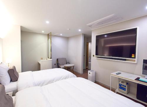 a hotel room with two beds and a flat screen tv at 사직 덴바스타 시그니처 호텔 in Busan