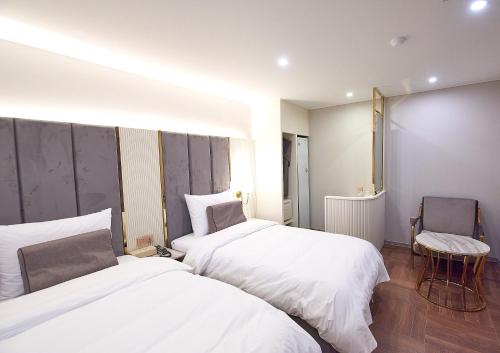 a hotel room with two beds and a chair at 사직 덴바스타 시그니처 호텔 in Busan