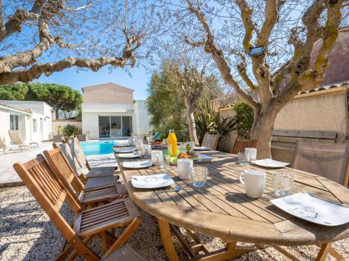 a wooden table and chairs in a yard at Holiday Home Villa du Littoral by Interhome in Le Grau-dʼAgde