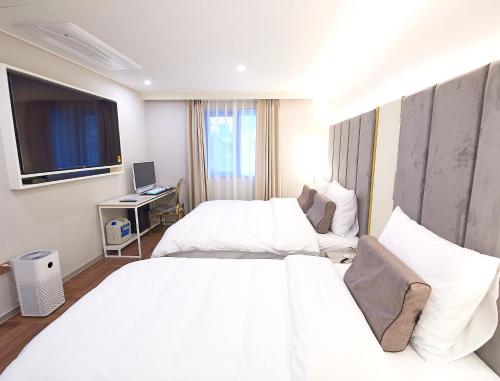 a hotel room with two beds and a television at 사직 덴바스타 시그니처 호텔 in Busan