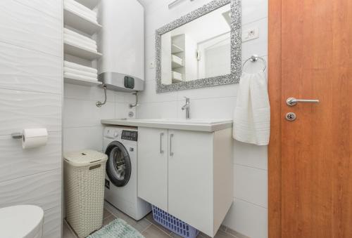 a bathroom with a sink and a washing machine at Apartmani Silvija in Makarska