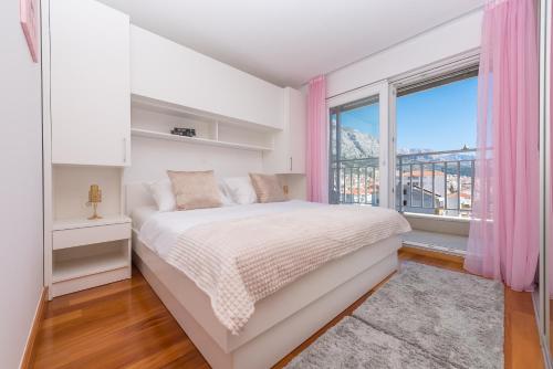 a white bedroom with a bed and a window at Apartmani Silvija in Makarska
