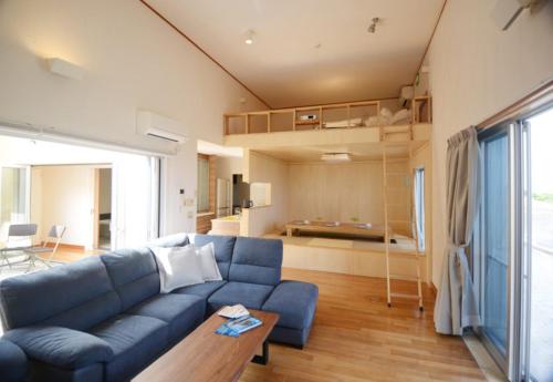 a living room with a blue couch and a kitchen at Kasane / The Family Villa in Ishigaki Island