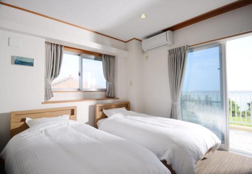 two beds in a bedroom with a large window at Kasane / The Family Villa in Ishigaki Island