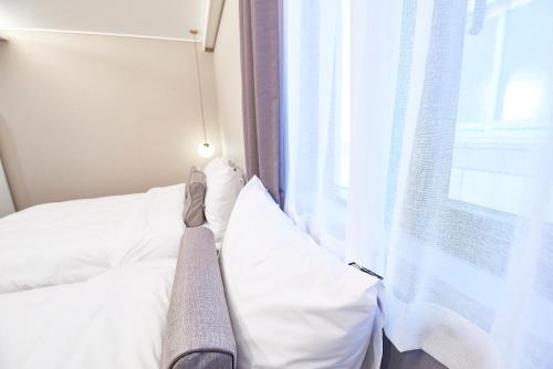 a bedroom with a bed with white sheets and a window at 사직 덴바스타 시그니처 호텔 in Busan