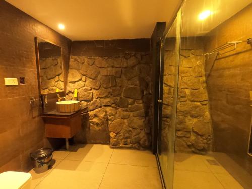 a stone bathroom with a shower and a sink at The Wild Trails Clarks Exotica , Munnar in Munnar