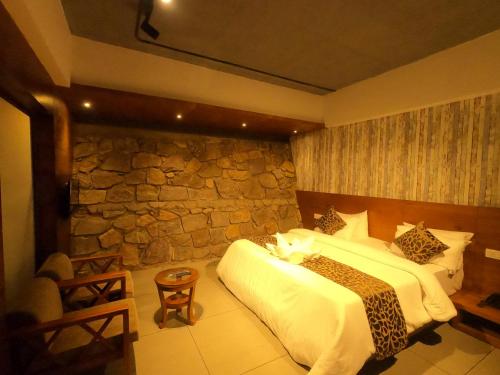 a bedroom with a bed and a stone wall at The Wild Trails Clarks Exotica , Munnar in Munnar