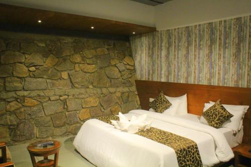 a bedroom with two beds and a stone wall at The Wild Trails Clarks Exotica , Munnar in Munnar