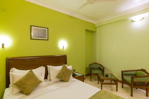 a bedroom with green walls and a bed and chairs at Crescent Park in Chennai