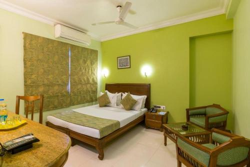 - une chambre avec un lit, une chaise et une table dans l'établissement Crescent Park, à Chennai