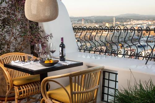a table and chairs on a balcony with wine glasses at Hotel La Torre del Canonigo - Small Luxury Hotels in Ibiza Town