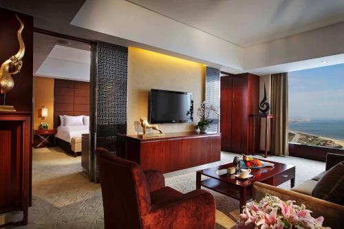 a living room with a television and a room with a bed at Crowne Plaza Yantai Sea View by IHG in Yantai