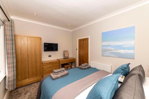 a bedroom with a blue bed and a tv at Breakspeare House in Scarborough