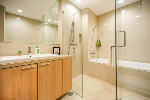 a bathroom with a shower and a sink and a tub at BUNGALOW by Kozystay 3BR Apartment at Kuningan in Jakarta