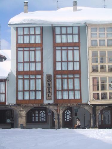 a building with a woman standing in front of it at HOSTAL SANCHO GARCIA in Espinosa de los Monteros