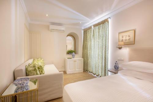 a bedroom with two beds and a couch and a window at Despotiko Hotel in Mýkonos City