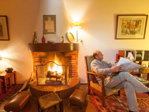 a man sitting in a chair in front of a fireplace at Dar Ness in Essaouira