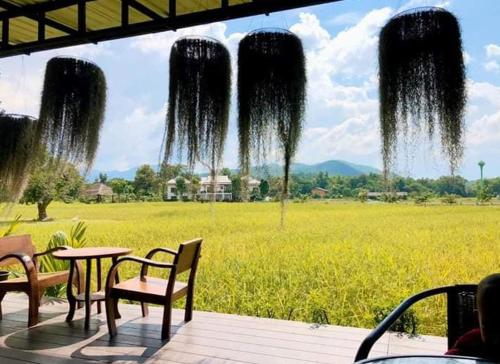 a patio with a table and chairs and a field at Oon Valley Farm Stay in Ban Mae Pha Haen