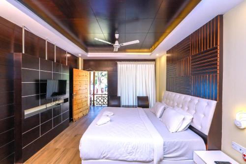 um quarto com uma cama branca e uma televisão em Pearl Park Beach Resort Private Limited em Port Blair