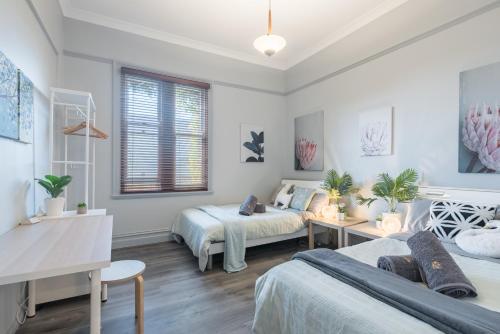 a bedroom with two beds and a table and a desk at Boutique Private Rm situated in the heart of Burwood 3 - ROOM ONLY in Sydney