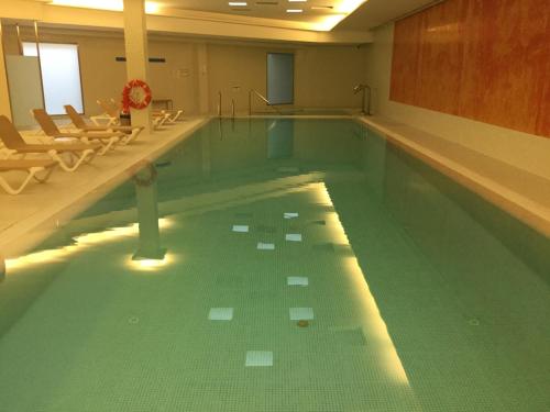 a large swimming pool with chairs in a building at Ribera del Marlin - Sotogrande in Sotogrande