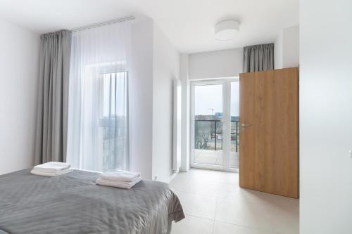 a white bedroom with a bed and a large window at Prima Playa in Międzyzdroje