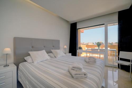 a bedroom with a large bed with two towels on it at Ribera del Marlin - Sotogrande in Sotogrande