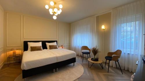 a bedroom with a bed and chairs and a chandelier at Casa Cappuccino duo studio in Groningen