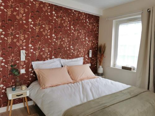 a bedroom with a bed with a red wall at Le Bois aux Cerfs in Bois-Jérôme-Saint-Ouen