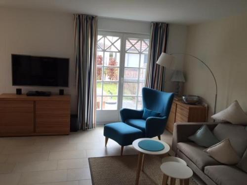 uma sala de estar com uma cadeira azul e um sofá em Lindenstr_ _Lille Hus 1_ em Zingst