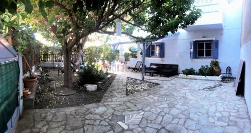 un patio de piedra con un árbol y un edificio en Blue Seaside House with Garden, en Skala Eresou