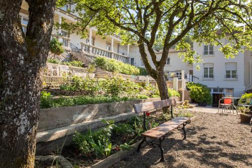 a park bench next to a tree and a building at Pension Gérard in Bourbonne-les-Bains