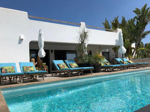 a pool with chaise lounge chairs next to a swimming pool at One Thousand Waves in Moraira