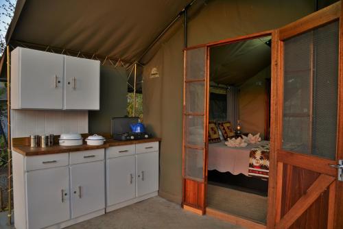 una cucina con armadi bianchi e un letto in una tenda. di Muchenje self-catering Tents a Chobe