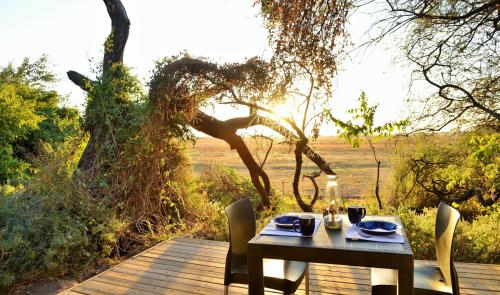 une table et des chaises assises sur une terrasse en bois dans l'établissement Muchenje self-catering Tents, à Chobe