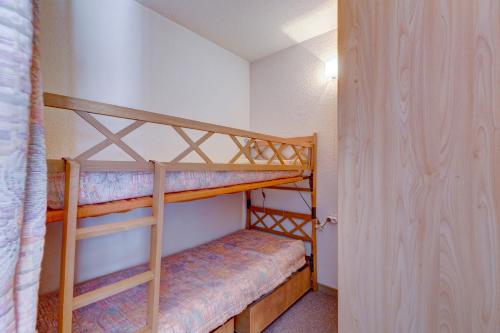 - 2 lits superposés dans une petite chambre avec une porte dans l'établissement Le Calao - appartement au Val d'Arly, à Flumet