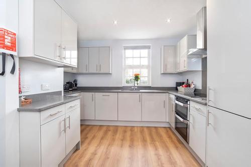 a white kitchen with white cabinets and a wooden floor at Thomas, Off Leeman Road in York