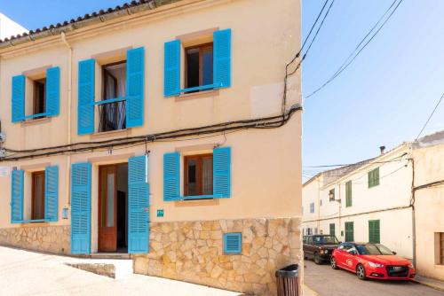 a building with blue shutters and a red car at Can Cosset Holiday Home in Capdepera