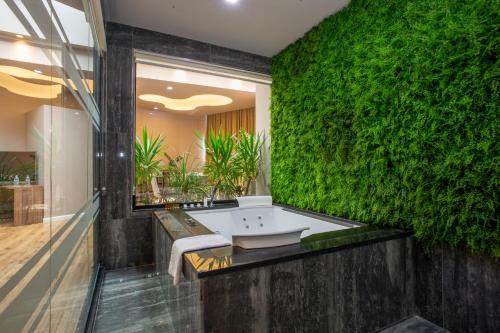 a bathroom with a green wall with a bath tub at Best Western Premier Ark Hotel in Tirana