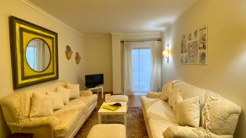 a living room with two white couches and a mirror at Downtown by Check-in Portugal in Faro