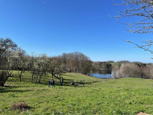 two people walking in a field next to a lake at Gîte du Mont Gérard in La Lanterne-et-les-Armonts
