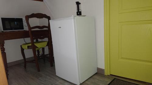 a white refrigerator in a room with a chair at Les Chambres du Relais in Liettres