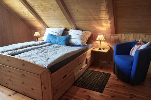 een slaapkamer met een groot bed en een blauwe stoel bij Birkmaase 3 Muschelblau OG in Zingst