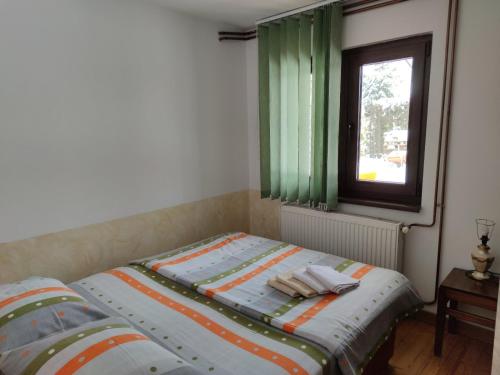 a bed in a bedroom with green curtains and a window at Privatni Smeštaj Tešević in Zlatibor